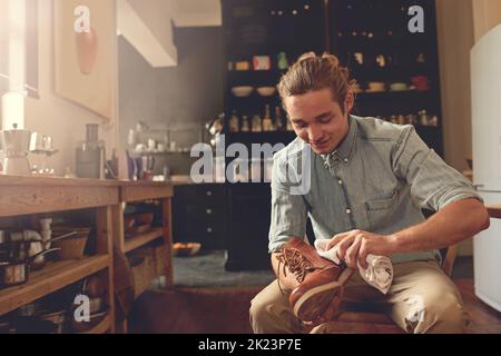 Tenere pulite le scarpe, un bel giovane che pulisce le scarpe in cucina. Foto Stock