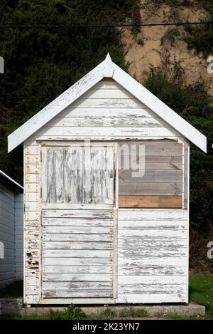 Singola capanna bianca sull'isola di Wight, Inghilterra, sbiadita e intemperita con ruggine e vernice che si staccano. Foto Stock