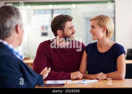 Voi qui quello. Giovane coppia che discute i piani di investimento con un consulente finanziario. Foto Stock