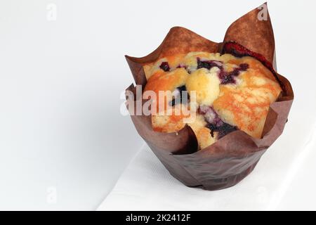 muffin ai mirtilli appena sfornati in un portabicchieri di carta su carta bianca Foto Stock