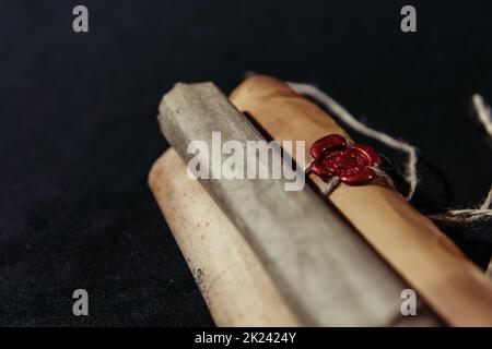 vista ravvicinata dei manoscritti arrotolati con sigillo in cera su sfondo nero, immagine stock Foto Stock