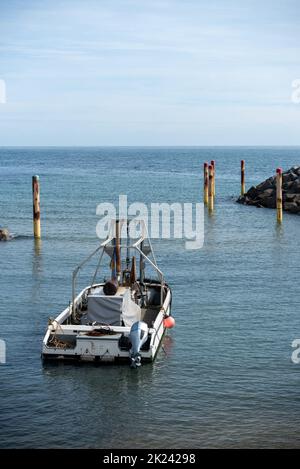 La barca ormeggiata vicino all'entrata di un piccolo porto sull'Isola di Wight, Inghilterra. Grandi massi su entrambi i lati come parte delle difese marine. Foto Stock