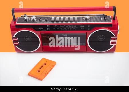 Lettore di nastri rosso vintage isolato su sfondo arancione e bianco Foto Stock