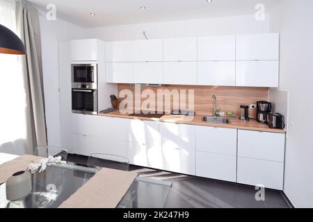 bella cucina bianca fresca ampia aperta grande con interni in legno e pavimento grigio Foto Stock