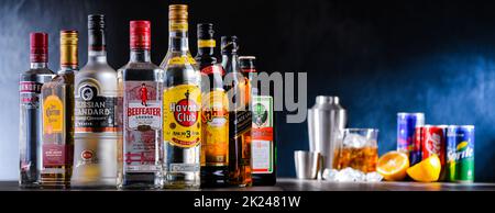 POZNAN, POL - DEC 28, 2021: Bottiglie di vari marchi internazionali di liquori duri e barman preparare una bevanda con un cocktail shaker Foto Stock