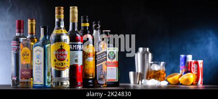 POZNAN, POL - DEC 28, 2021: Bottiglie di vari marchi internazionali di liquori duri e barman preparare una bevanda con un cocktail shaker Foto Stock