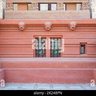 Due finestre adiacenti in ferro battuto a griglia installate nella parete ornamentale all'esterno di un vecchio edificio in pietra Foto Stock