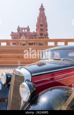 Cairo, Egitto - 29 2020 luglio: 1953 auto d'epoca Mercedes nera e rossa, con il Palazzo Barone Empain all'estremità lontana, quartiere Heliopolis Foto Stock