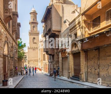 Cairo, Egitto - Giugno 26 2020: Moez Street con i lavoratori, pochi visitatori locali e minareto del complesso Qalawun edificio storico, durante Covid-19 Lockdown pe Foto Stock