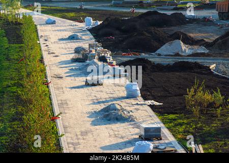 sistemazione di un'area ricreativa verde, preparazione per la posa dei cavi di illuminazione, architettura paesaggistica e posa di piastrelle sui sentieri, focalizzazione selettiva Foto Stock