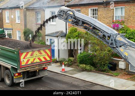 Rimozione meccanizzata della vecchia superficie stradale prima del ripavimentamento di una strada residenziale a Twickenham, Greater London, UK. Sarà rifatto con asfalto dopo aver rimosso l'asfalto precedentemente usurato e punteggiato. (132) Foto Stock