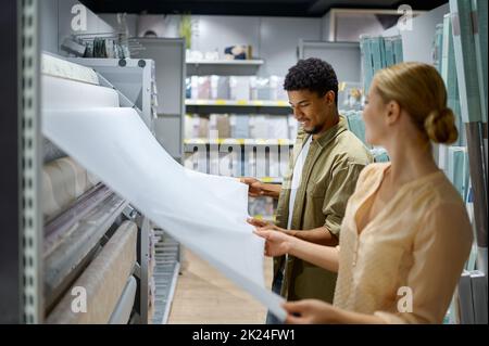 Giovane coppia multietnica scegliendo il colore della carta da parati per il nuovo appartamento. Shopping per la ristrutturazione della casa Foto Stock