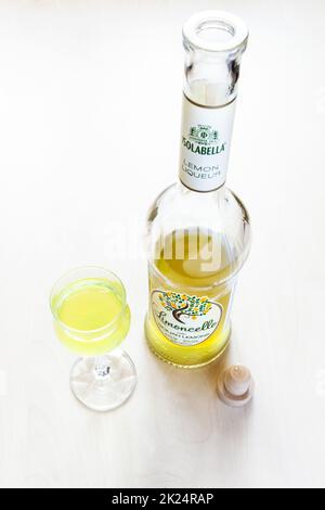 Mosca, Russia - 20 marzo 2022: Bicchiere di liquore e bottiglia aperta di siciliano Isolabella Limoncello su tavola pallida. Limoncello è liquore al limone italiano ma Foto Stock