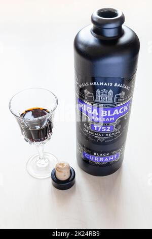 Mosca, Russia - 20 marzo 2022: Vetro e bottiglia di riga Balsam nero su tavola pallida. Riga Black Balsam è probabilmente il più antico amaro del mondo, Th Foto Stock
