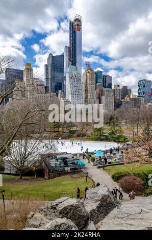 Wollman Rink con People Ice Skating durante il giorno d'inverno, vista dalla distanza, Central Park New York City, panchine e persone che camminano nel f Foto Stock