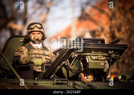 Bucarest, Romania - 1 dicembre 2021: Un soldato si erge sul tetto di un portatore di personale blindato, durante una parata militare a Bucarest, Roma Foto Stock