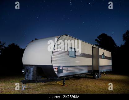 Rimorchio di viaggio su un campo erboso con stelle luminose sopra di notte Foto Stock