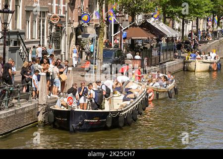 Amsterdam, Paesi Bassi - Agosto 2022: I turisti salendo su un battello turistico sul canale nel centro della città Foto Stock