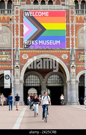 Amsterdam, Paesi Bassi - 2022 agosto: Persone in bicicletta di fronte al famoso Museo Rijks nel centro della città Foto Stock