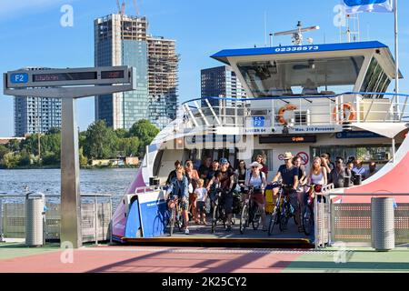 Amsterdam, Paesi Bassi - 2022 agosto: Persone in bicicletta in procinto di scendere da un servizio di traghetto navetta sul lungomare di Amsterdam Foto Stock