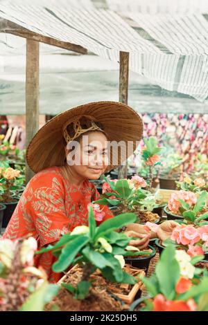 Donna asiatica felice con cappello di paglia vietnamita vaso fiori nel suo giardino Foto Stock