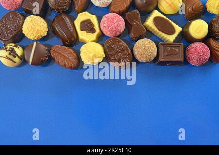 Biscotti al cioccolato e praline per un evento di vacanza su sfondo blu scuro con ampio spazio per copie. Disposizione piatta Foto Stock