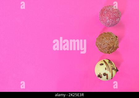 Collezione di dolci al cioccolato su sfondo colorato. Praline al cioccolato su sfondo rosa pastello con spazio per la copia. Disposizione piatta, vista dall'alto Foto Stock