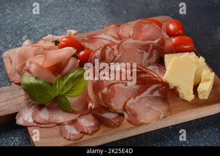 Spalla italiana di maiale stagionato. Antipasto piatto coppa stagionata e pomodori ciliegini. Salsiccia tradizionale affettata con spezie Foto Stock