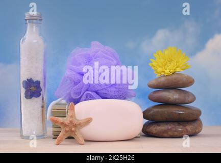 Sapone e pietre da massaggio con conchiglie di mare su sfondo cielo blu Foto Stock