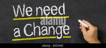 Testo scritto su una lavagna - abbiamo bisogno di un cambiamento Foto Stock