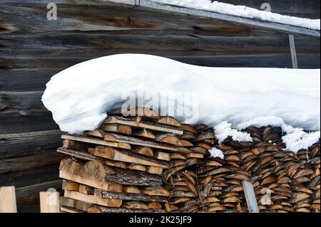 Legno accatastato in un palo di legno sotto la neve in inverno Foto Stock