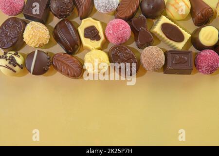 Biscotti al cioccolato e praline per un evento di vacanza su sfondo dorato con ampio spazio per copie. Disposizione piatta Foto Stock