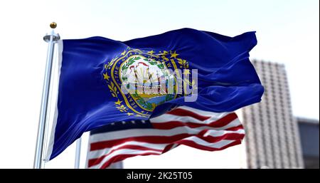 La bandiera dello stato americano del New Hampshire ondola nel vento con la bandiera americana offuscata sullo sfondo Foto Stock