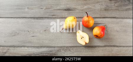 Quattro pere mature, uno tagliato a metà, table top view, ampio formato banner. Foto Stock