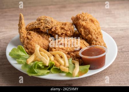 Pollo fritto e patata con foglia di rosmarino, cibo spazzatura ad alto contenuto calorico servito su piatto bianco Foto Stock