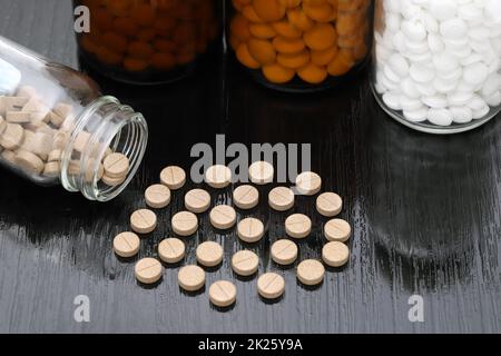 pillole mediche e bottiglia di vetro su tavolo di legno nero Foto Stock