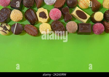 Biscotti al cioccolato e praline per un evento di vacanza su sfondo verde chiaro con ampio spazio per copie. Disposizione piatta Foto Stock