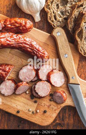 Salsicce di maiale affumicate. Salame affettato su tagliere. Foto Stock