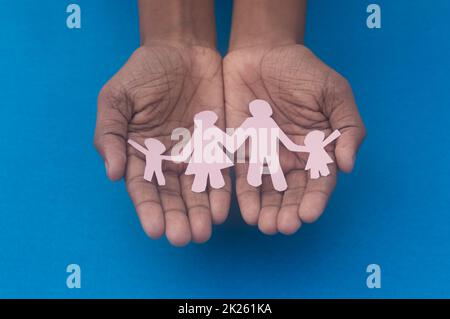 Vista dall'alto dell'intaglio della famiglia con presa a mano. Giornata mondiale della salute protezione contro la violenza domestica, l'assistenza sanitaria e il background medico. Promuovere l'assistenza, il sostegno ai senzatetto e il concetto di allontanamento sociale. Foto Stock