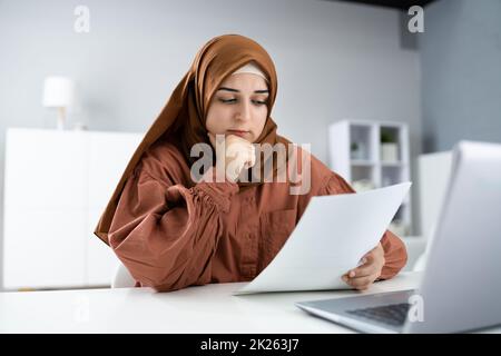 Preoccupata Donna musulmana che fa le tasse Foto Stock