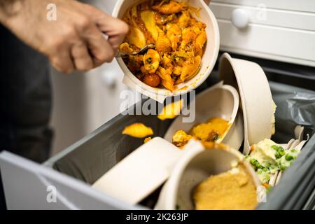 Gettare via cibo residuo nel cestino Foto Stock