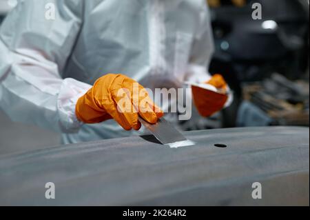 Meccanico impegnato nella riparazione locale della carrozzeria Foto Stock