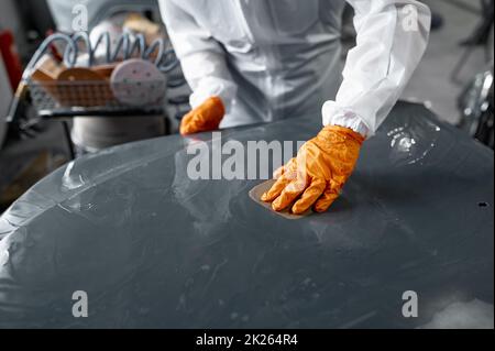 Meccanico in carrozzeria auto verniciata con levigatura uniforme Foto Stock