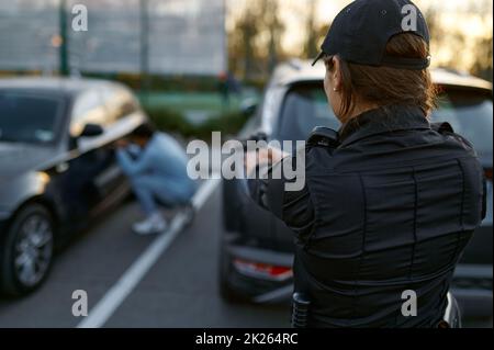 Poliziotto che punta la pistola al ritorno del ladro dell'automobile Foto Stock