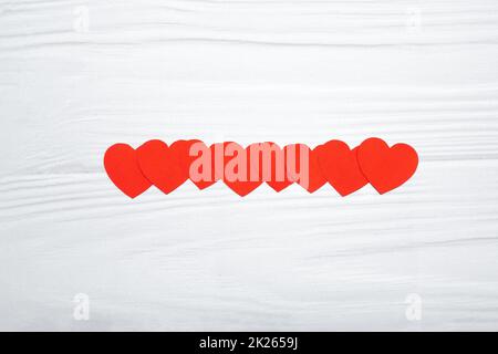 Cuori di carta rossa appesi su sfondo di legno bianco Foto Stock