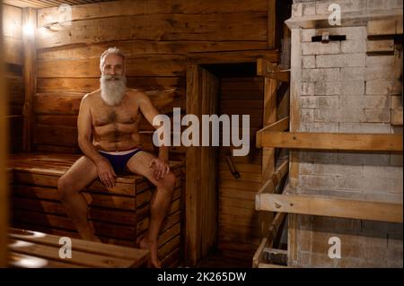 Il resto dell'uomo anziano grigio-haired alla casa del bagno Foto Stock