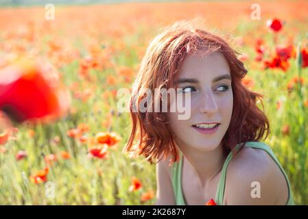 ragazza giovane felice con capelli rossi in campo papavero Foto Stock