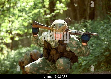 Esperienza militare completa - un giorno commando - correre attraverso l'acqua con la replica automatica del fucile Foto Stock