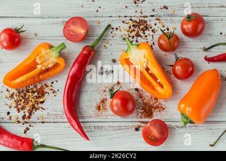 Peperoni assortiti, pomodori ciliegini e spezie su sfondo chiaro. Condimenti per cibo. Foto Stock