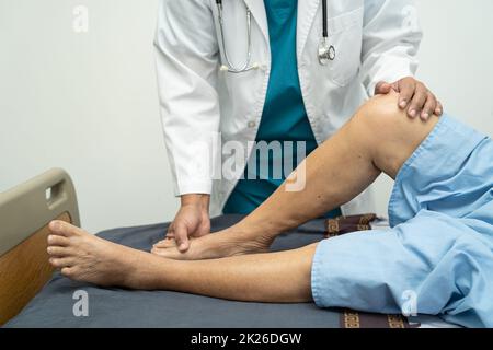 Medico asiatico fisioterapista esame, massaggio e trattamento ginocchio e gamba di paziente anziano in ospedale medico ambulatorio ortopedist infermiere. Foto Stock